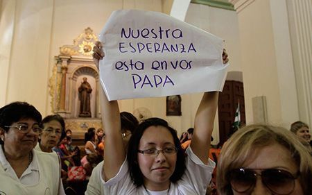 Una mujer alza un cartel durante la visita del papa Francisco a la catedral de Asunción (Paraguay). 