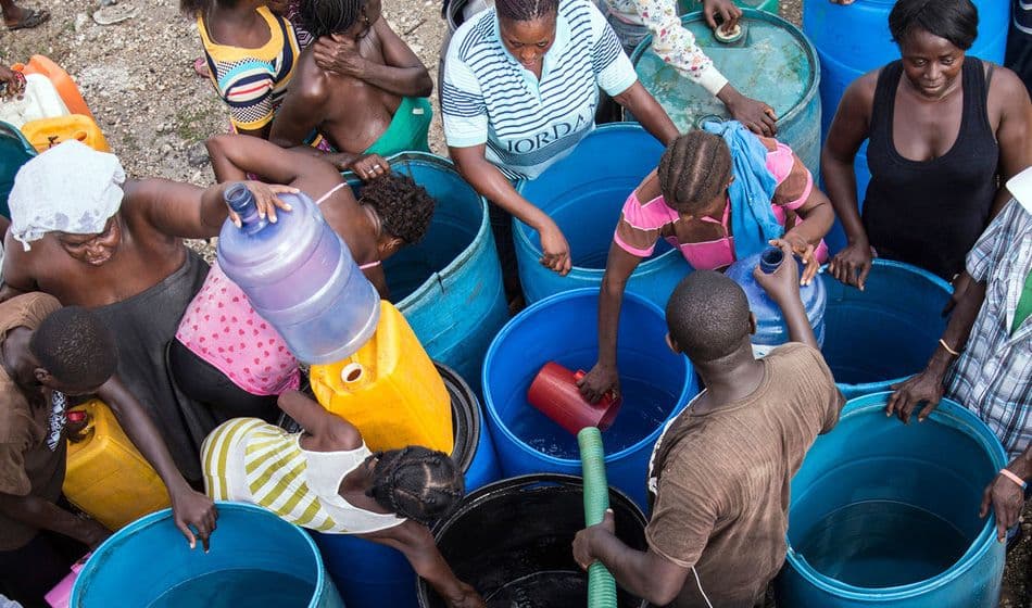 La gente afectada por el huracán Matthew, en Haití, traslada agua limpia en cubos para poder llevarla a casa. UNICEF/UN038103/LeMoyne